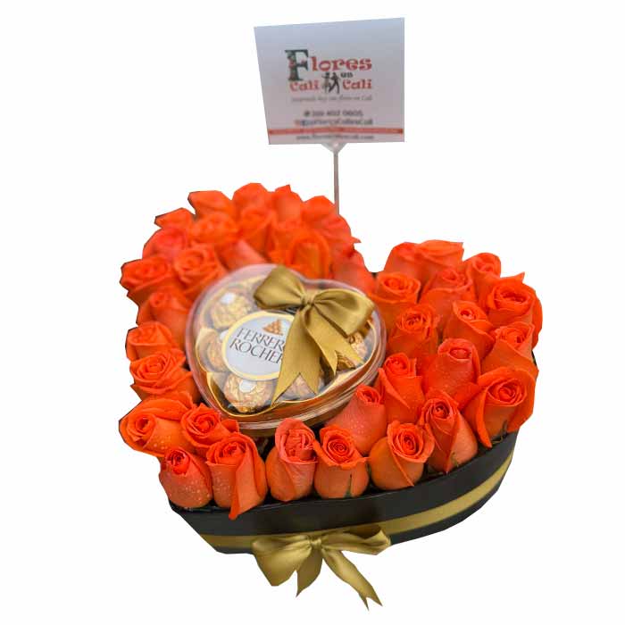 Hermoso corazon de rosas naranjas con chocolates